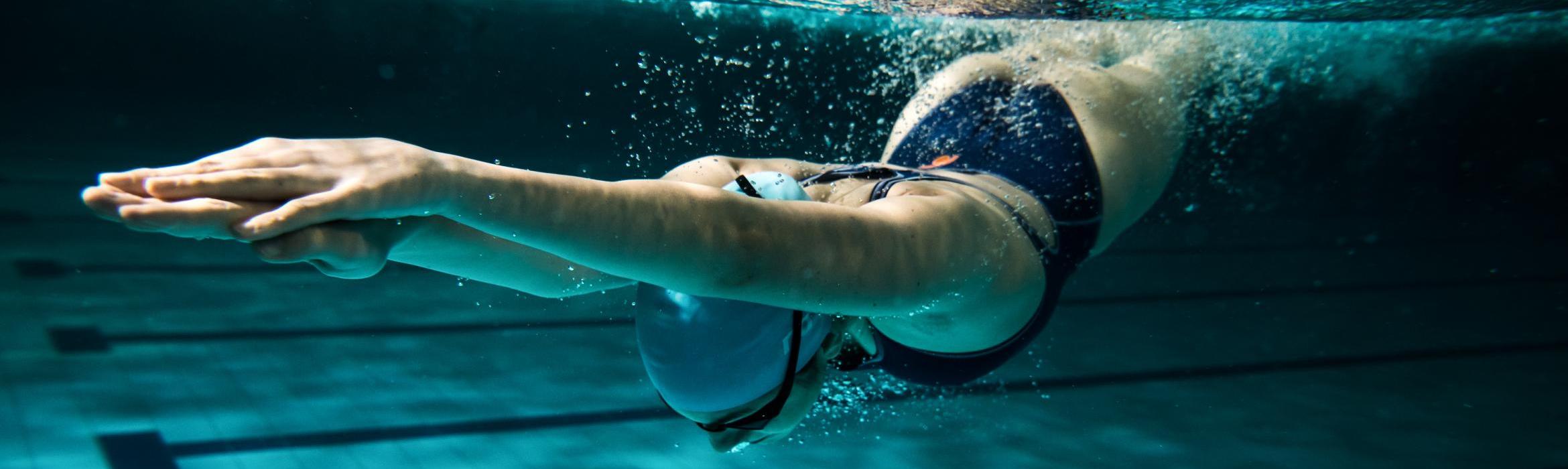 Mujer entrando de cabeza en piscina, foto bajo el agua